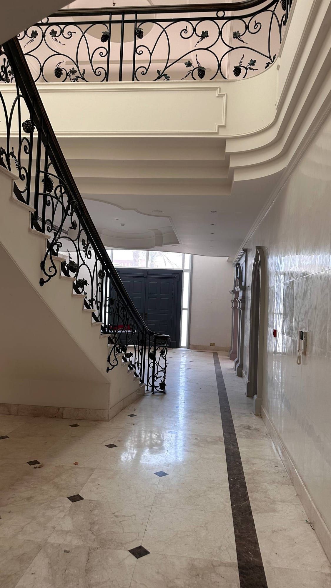 Staircase hall with a wrought-iron balustrade and a polished stone floor