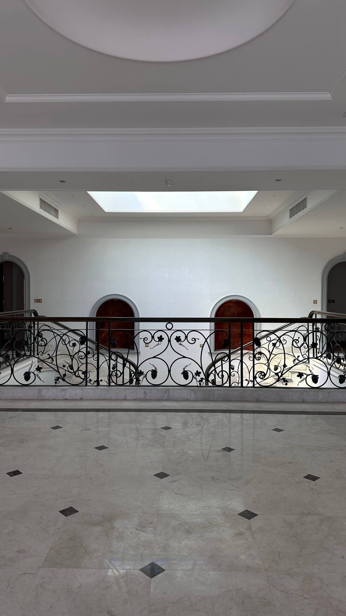 Upper gallery with a skylight, arched doorways and an iron balustrade