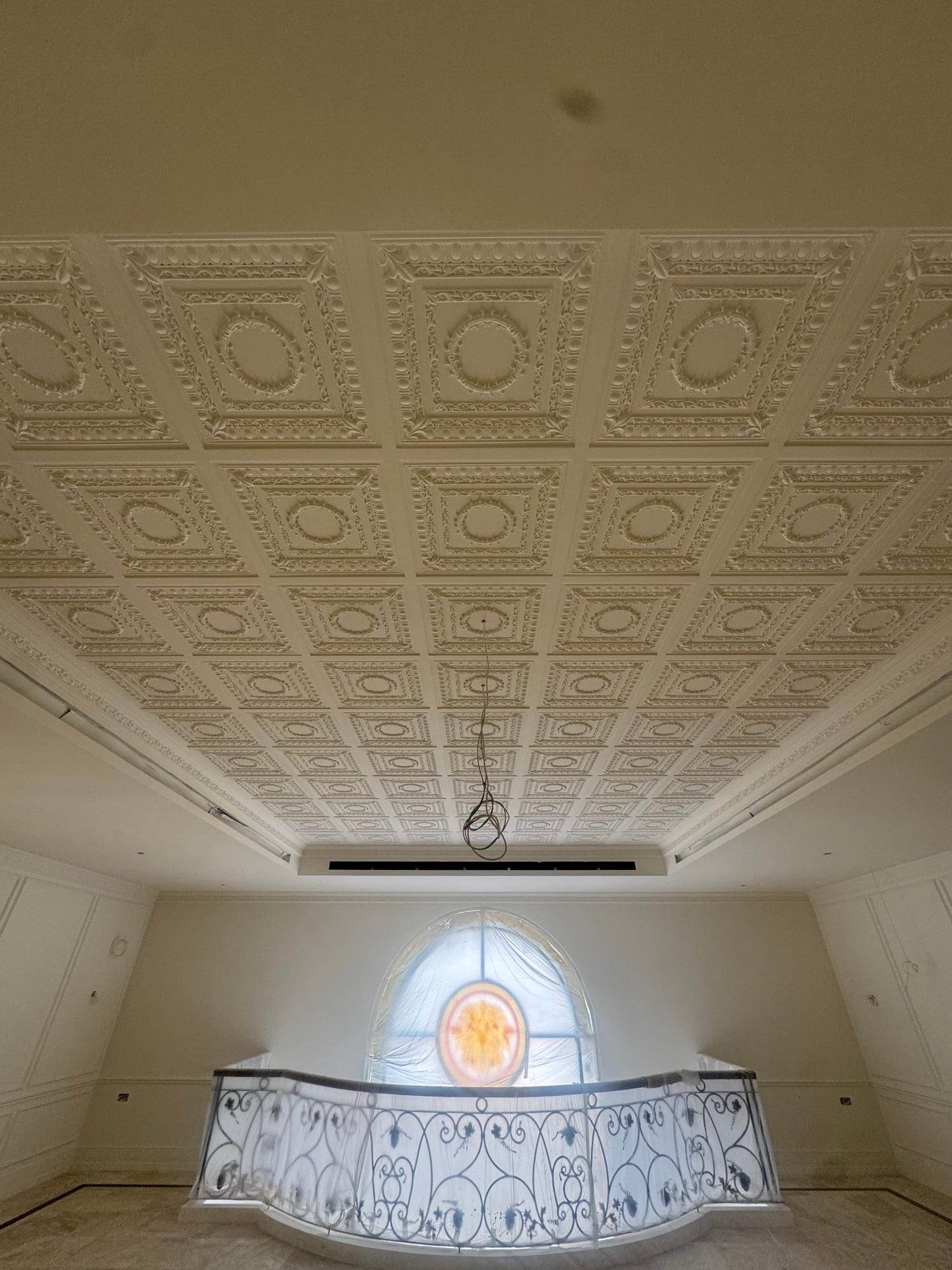 Coffered plaster ceiling over the upper gallery, above a curved balustrade and a stained-glass window