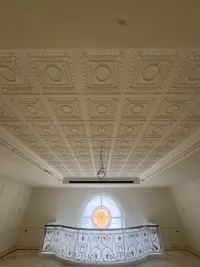 Coffered plaster ceiling over the upper gallery, above a curved balustrade and a stained-glass window