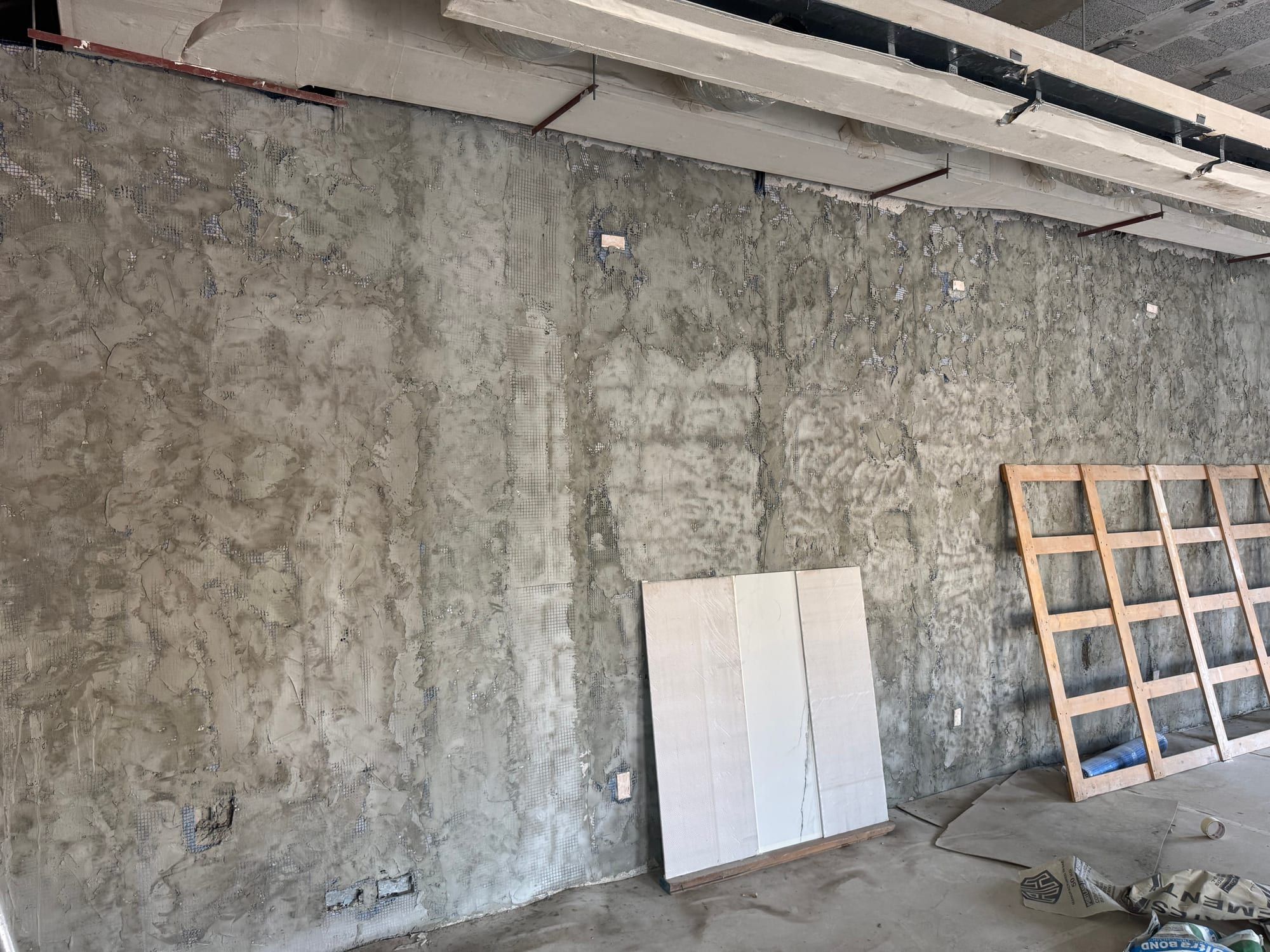 Internal wall with the old plaster removed down to bare blockwork, loose panels leaning against it