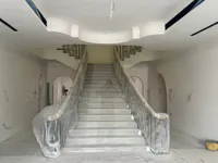 Double staircase under protective wrap in the entrance hall, with the stepped ceiling above