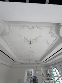 White ceiling with scrolled plaster ornaments set inside stepped levels