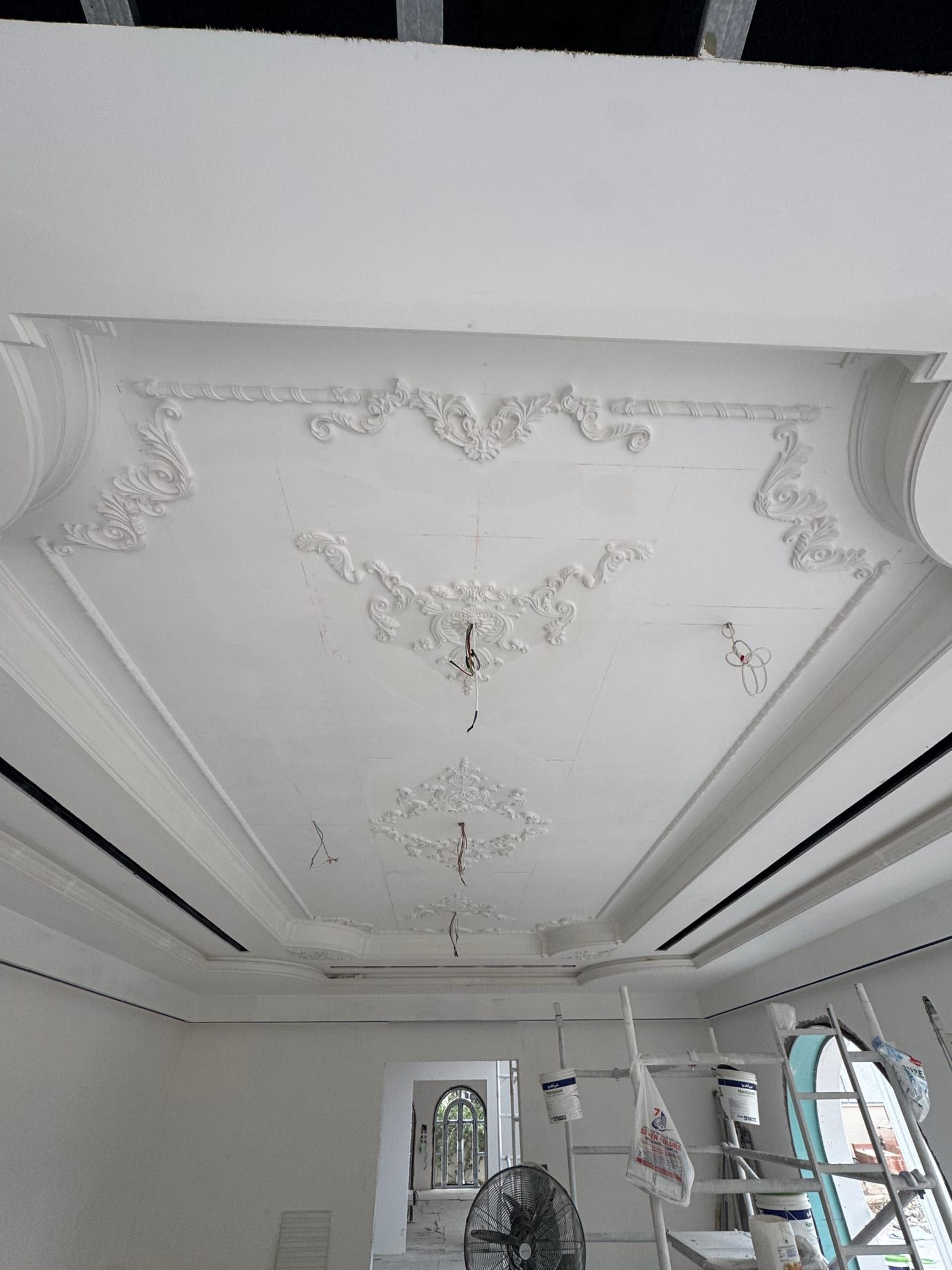 White ceiling with scrolled plaster ornaments set inside stepped levels