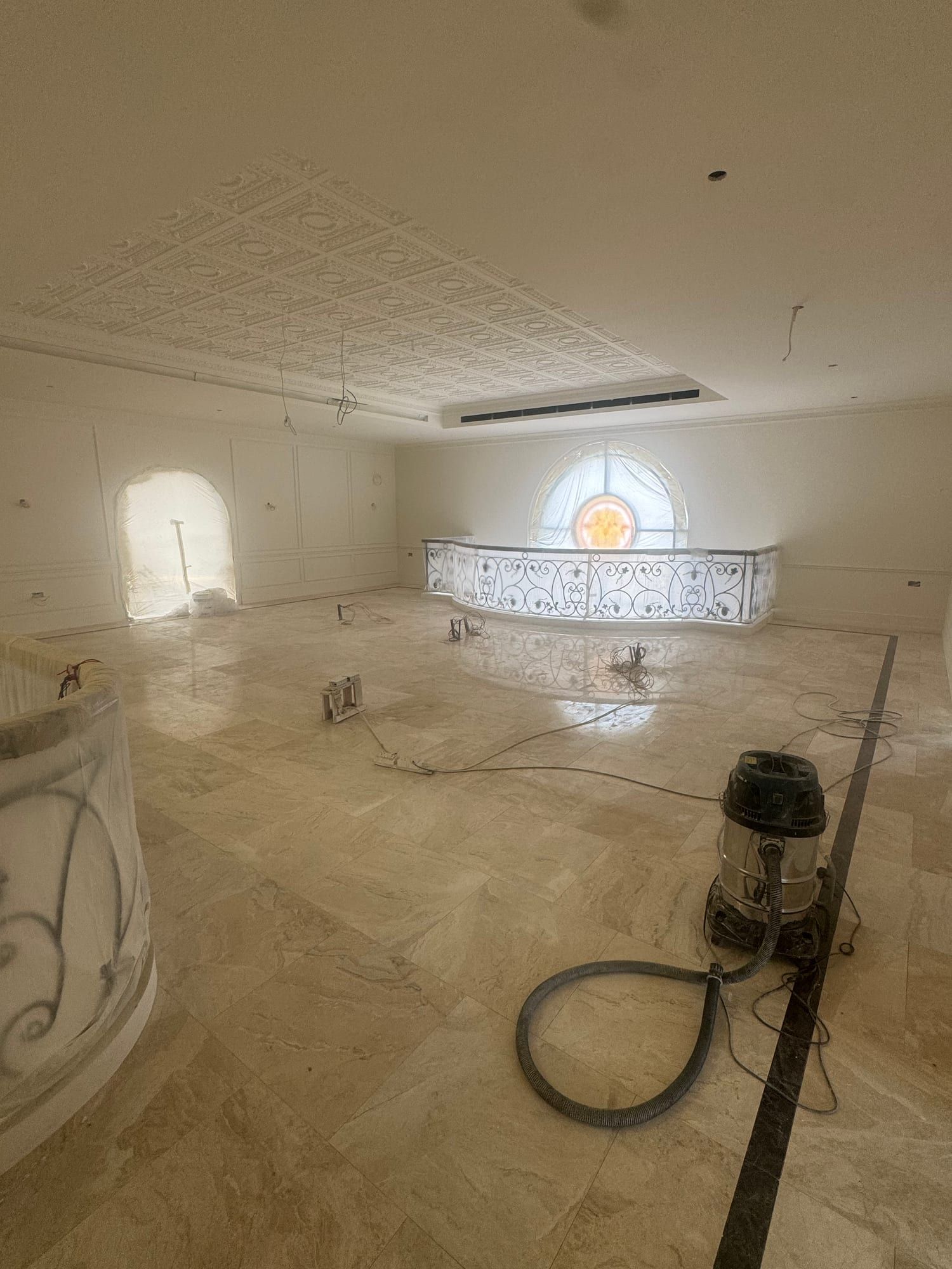 Upper gallery with a newly laid pale stone floor, a curved iron balustrade and a coffered ceiling